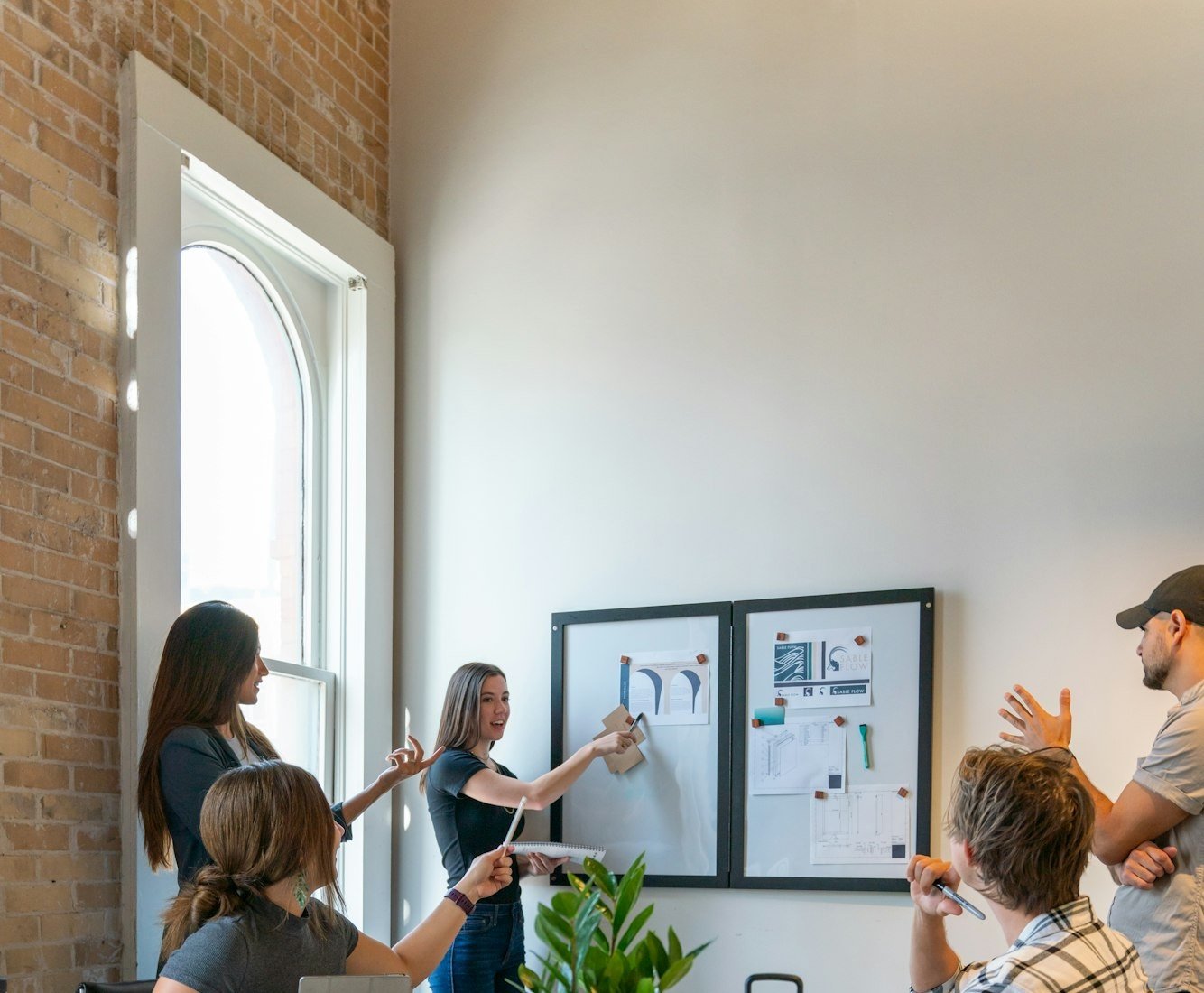 Une équipe réunie autour d’un tableau d’affichage, dans une salle aux murs de brique