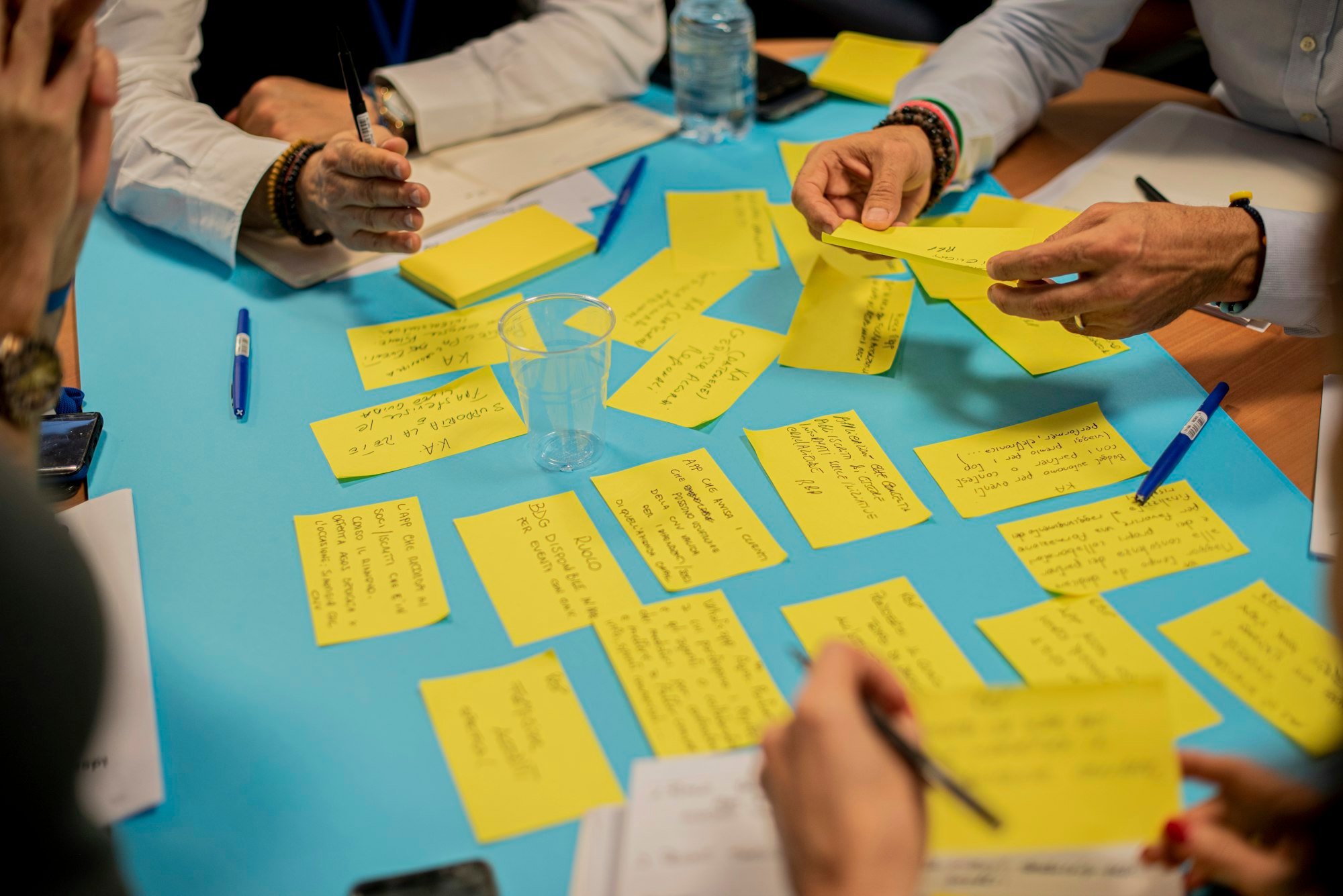 Une équipe trie des notes autocollantes jaunes sur une grande table