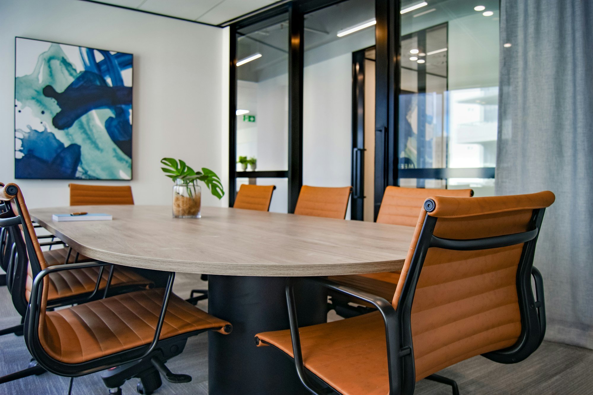 Une salle de réunion lumineuse avec une table ovale et des fauteuils en cuir
